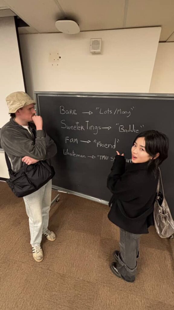 カナダのトロント大学に正規留学されているりほさんが、黒板の前で黒板に書かれている内容について議論している写真