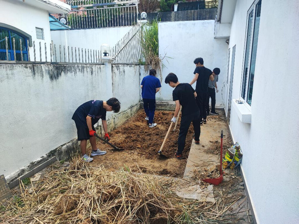 マレーシアAPU大学に通うR.M.さんが仲間とともに庭を整備している